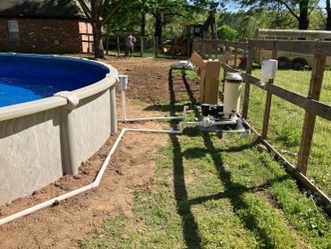 Outdoor pool setup with filtration system and construction in progress.
