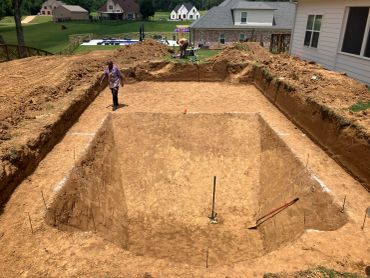 Excavation site with workers preparing a large pit near houses.