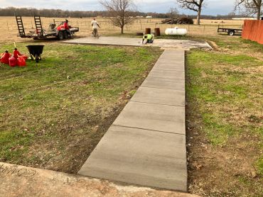 Workers finishing a freshly poured concrete slab in a rural area.