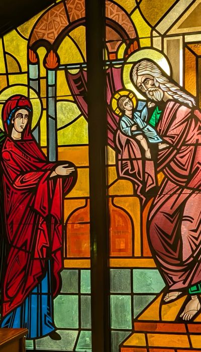Stained glass depicting a religious scene with a woman and a man holding a child.