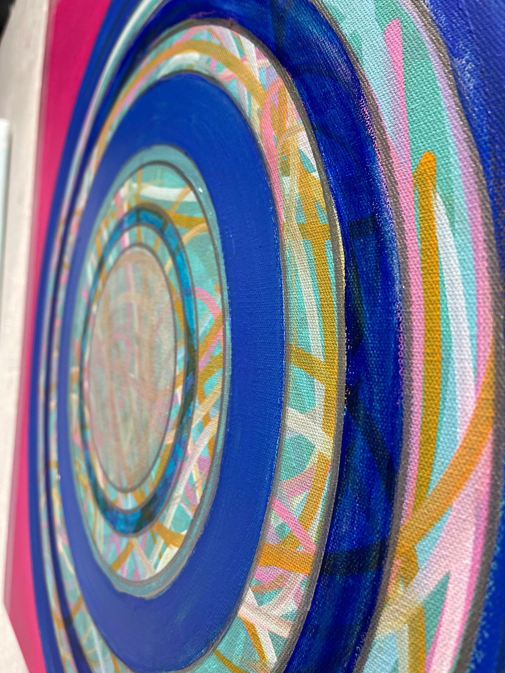 Close-up of colorful concentric circles with intricate patterns on canvas.
