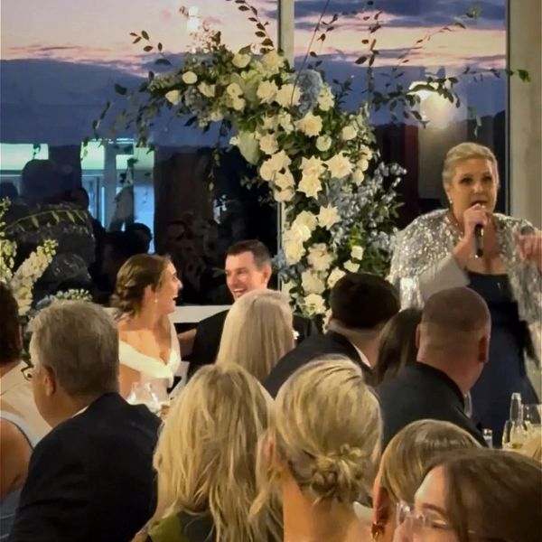 Couple laughing at a wedding reception with a singer.