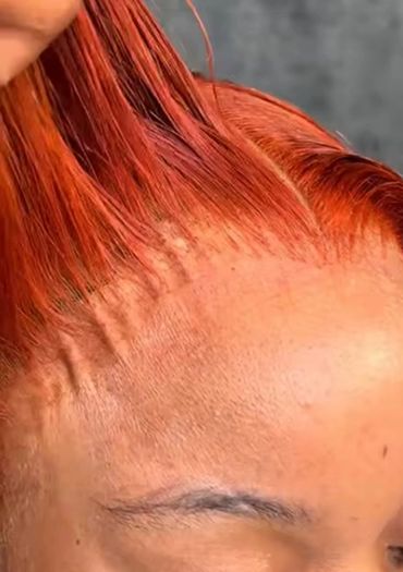 Close-up of vibrant red hair being styled near the hairline.