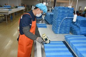 Factory worker on cutting floor cutting a mop pattern 