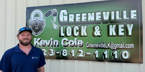 Man standing beside a Greeneville Lock & Key business sign.