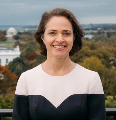 Smiling woman in a black and white dress with a scenic city backdrop.