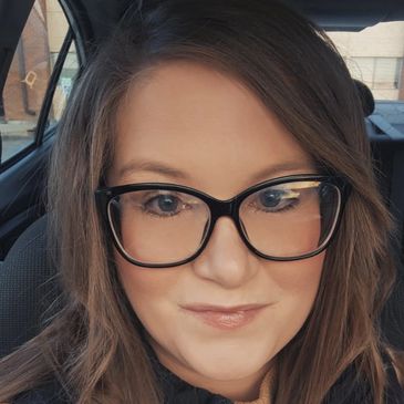 Woman with glasses smiling inside a car.