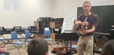 Joe Jewett teaching violin class in Montana