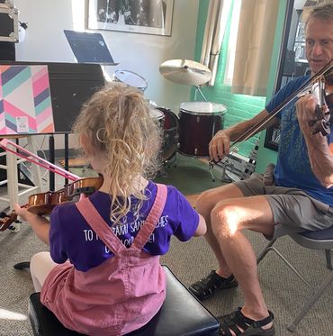 Joe Jewett teaches a young violin student in a music room