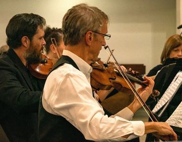 Joe Jewett performing violin with other violinists in concert