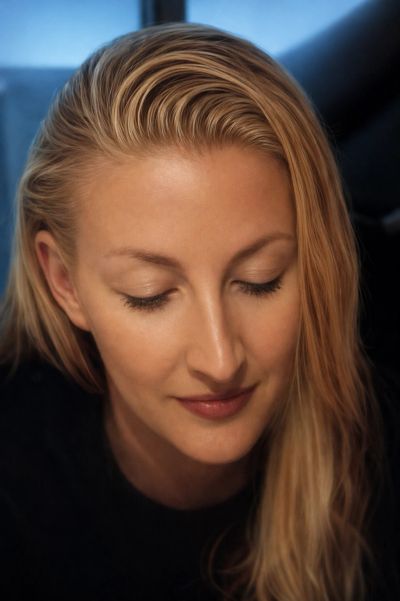 Close-up of a serene blonde woman with eyes closed and a gentle smile.