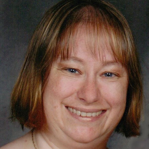 Janice Christian, close-up portrait of a smiling woman with short hair and blue eyes.