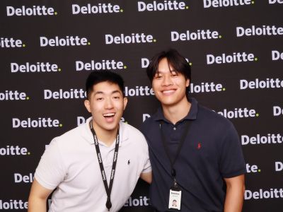 Guests posing at a FlashFolio Booth photo booth with a branded Deloitte step-and-repeat backdrop at