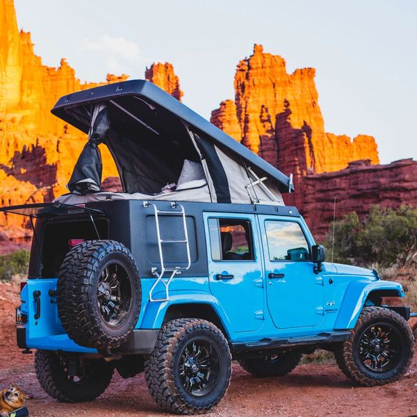 A 4-door Jeep Wrangler with pop-up camper top conversion parked at a campground near Moab