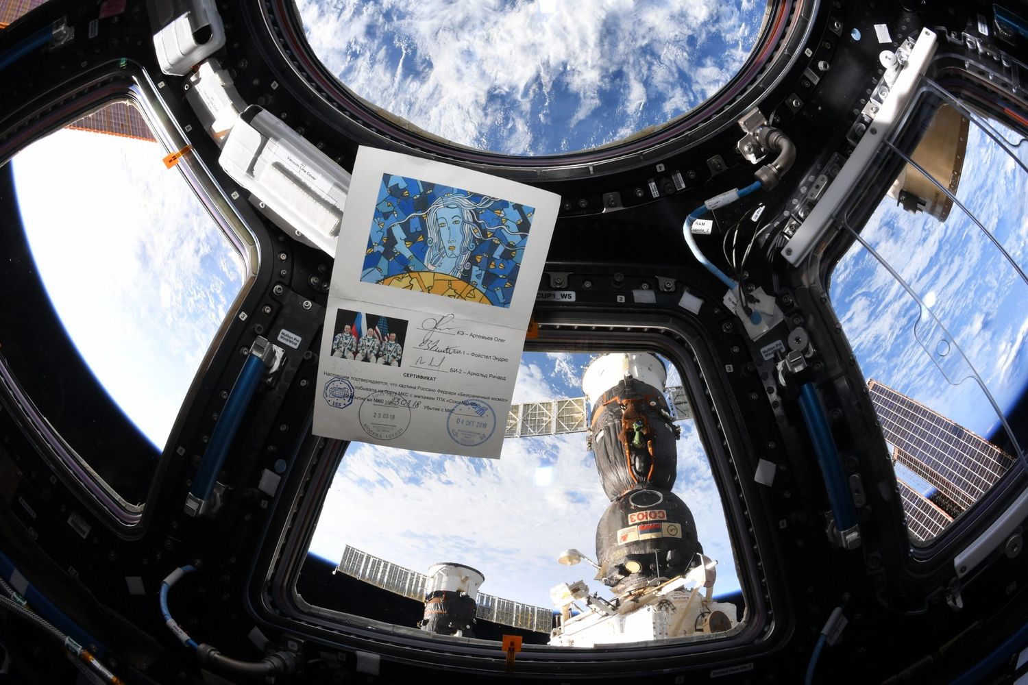 Foto del dipinto scattata sulla ISS autografata dai tre astronauti della missione