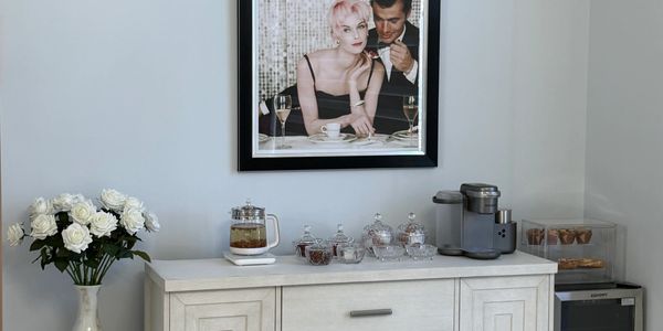 Elegant tea setup with glass jars, a coffee machine, and a framed stylish photo on the wall.