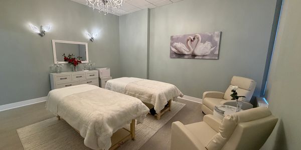 A serene massage room with two beds and soft lighting.