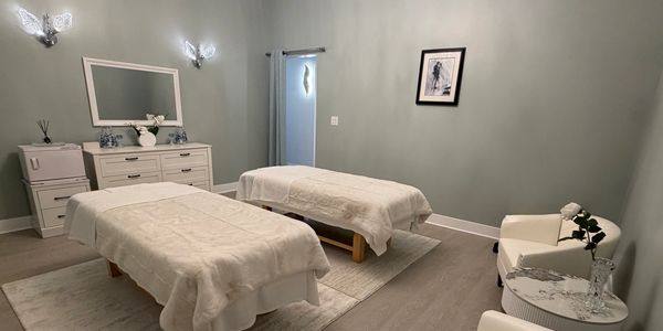 A serene massage room with two beds and soft lighting.