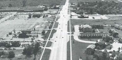 Aerial view of a small town's main road and surrounding buildings.