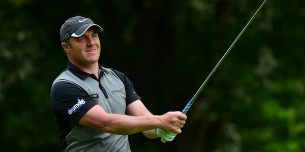 Golfer swinging a club on a green course.