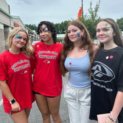 Four young women with face paint smiling outdoors.
