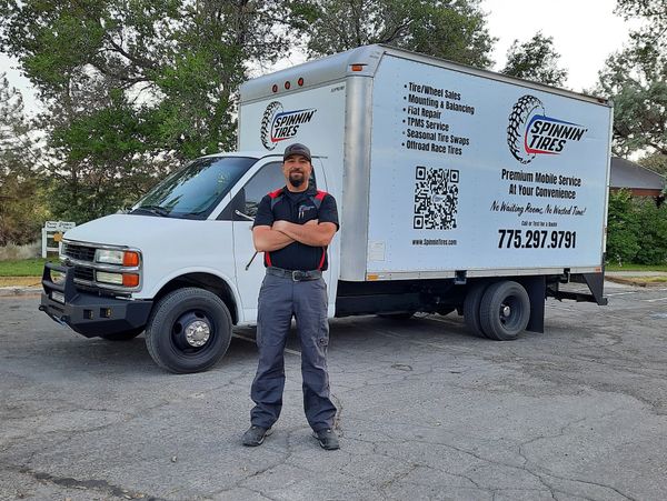 Man standing confidently in front of a Spinnin' Tires mobile service truck.
