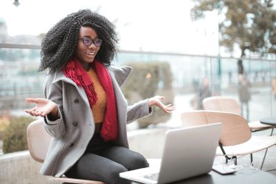 A woman happily video chatting on her laptop outdoors in a casual setting.