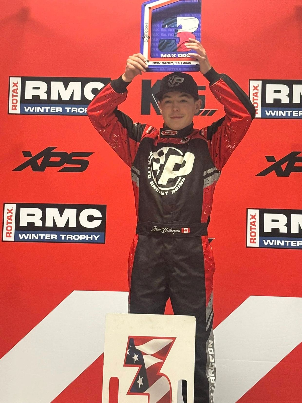 Race car driver celebrating with a trophy on the podium.