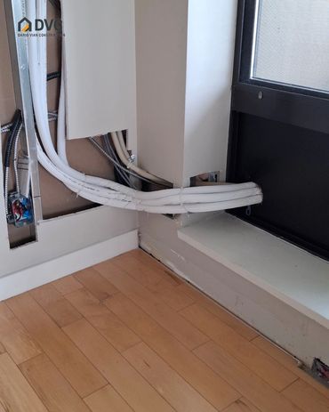 Exposed lines and open wall sections beside a window before repair