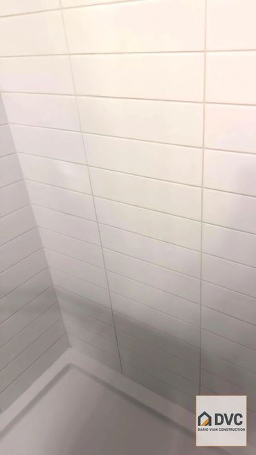 Clean white tiled shower corner with Dario Vian Construction logo.