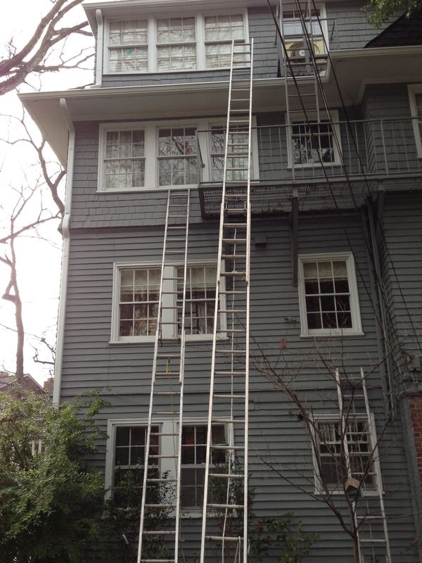 Large gray house with several ladders 