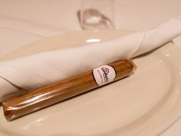 A wrapped cigar with a napkin on a white plate.