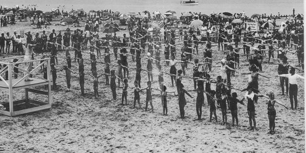 Crowd performing synchronized exercise on a beach.