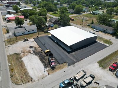 Aerial view of a new building with freshly paved surrounding area and construction vehicles.