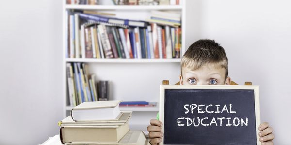 Young boy holding a chalkboard with 'Special Education' written on it.