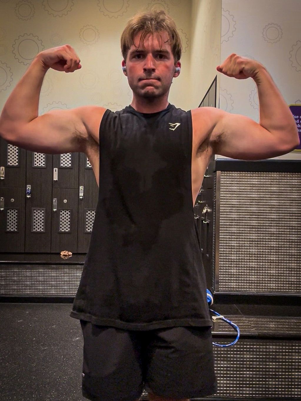 Young man flexing muscles in a gym.