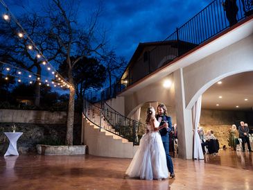 Couple sharing a dance under string lights at night.