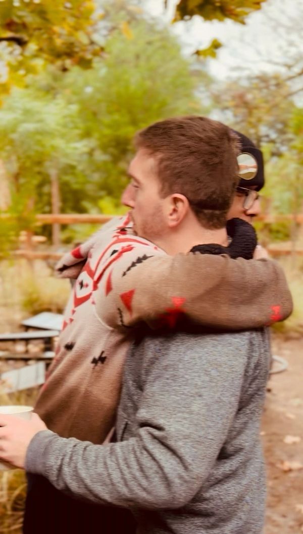 Two people warmly hugging outdoors in autumn.
