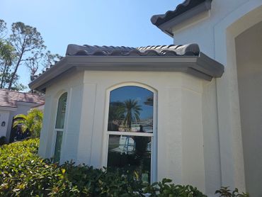 Sunny exterior view of a house with arched windows and a tile roof.