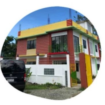 Two-story colorful house with a black vehicle parked outside.