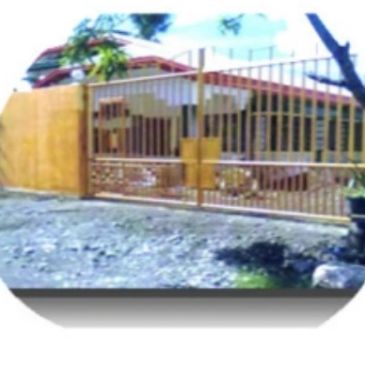 Yellow metal fence and gate surrounding a house.