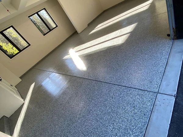 Empty garage with polished speckled floor and sunlight through windows.