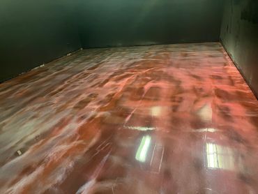 A room with a shiny, marbled reddish floor and dark green walls.