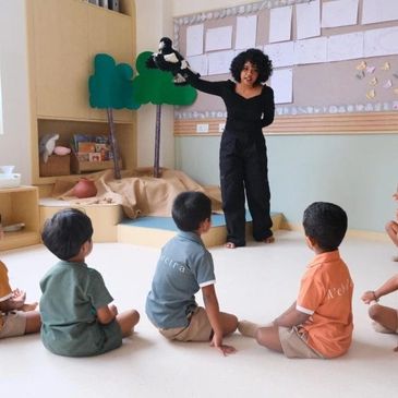 Teacher showing puppet to children in classroom.
