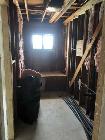 Bathroom area post demolition with exposed insulation and bathrub