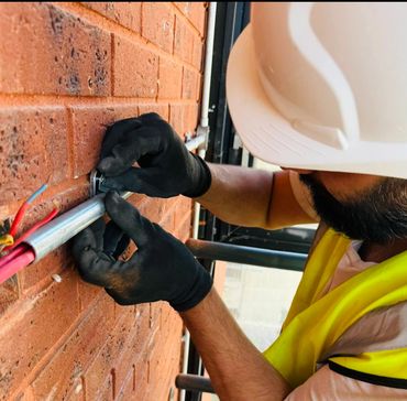 Electrician installing conduit and wires on a brick wall.