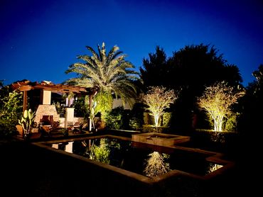 Landscape and stonework are highlighted with landscape lighting around the pool.