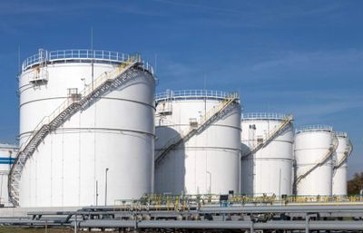 Large white industrial storage tanks with staircases under a clear blue sky.