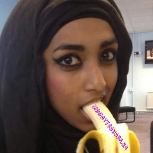 Woman wearing a hijab eating a banana indoors.