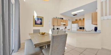 Modern dining area with wooden table and kitchen in background.